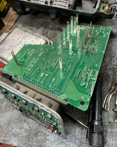 Green circuit board with pins, next to a small circuit board and a flashlight.
