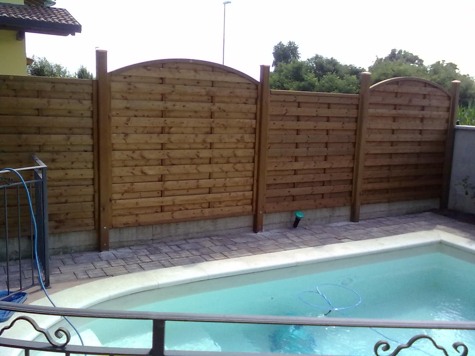 Piscina nel cortile sul retro, adiacente a una recinzione in legno che garantisce la privacy e a un patio pavimentato.