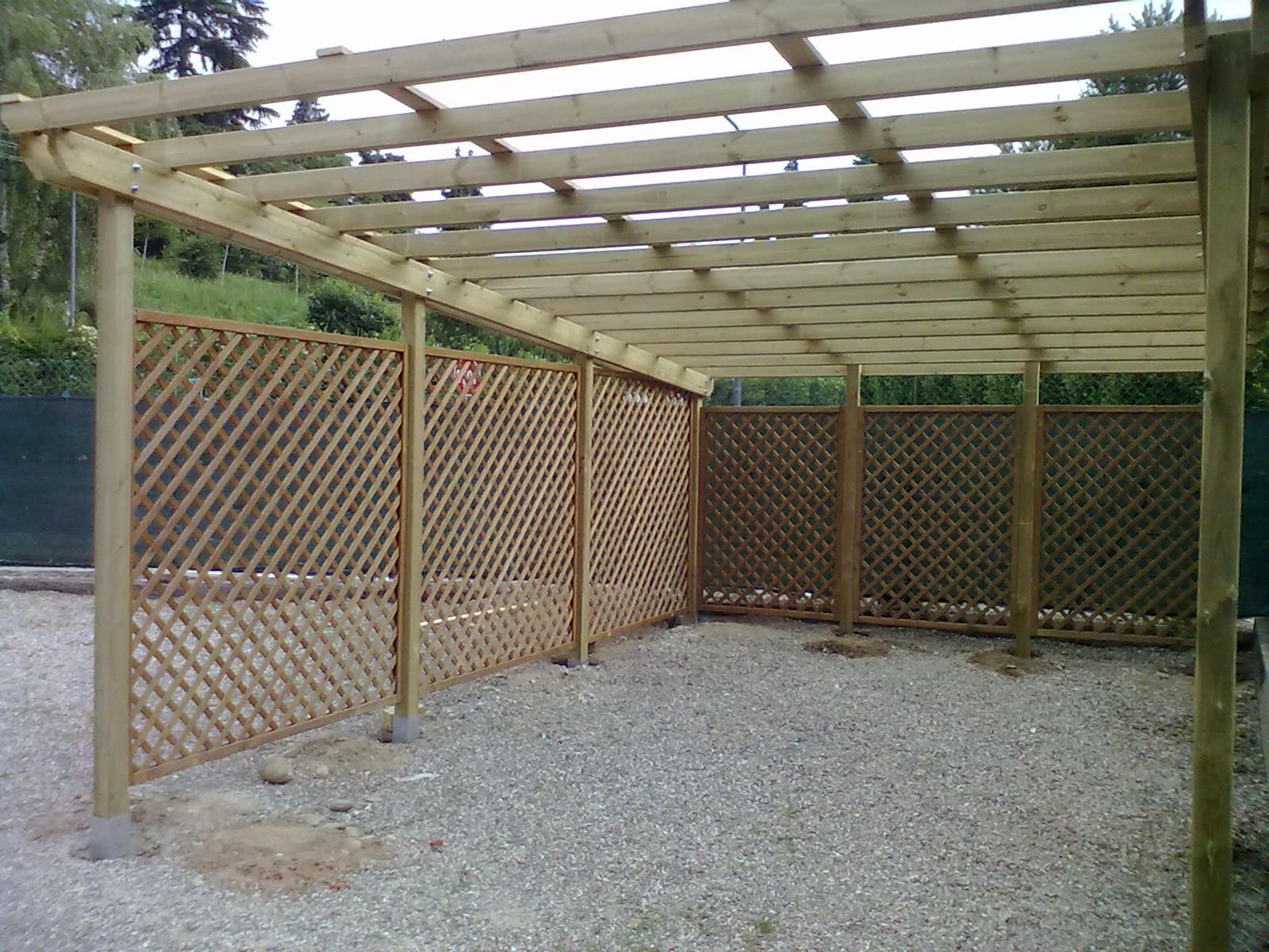 Struttura a pergola in legno con pareti divisorie a griglia sopra un patio di ghiaia all'aperto