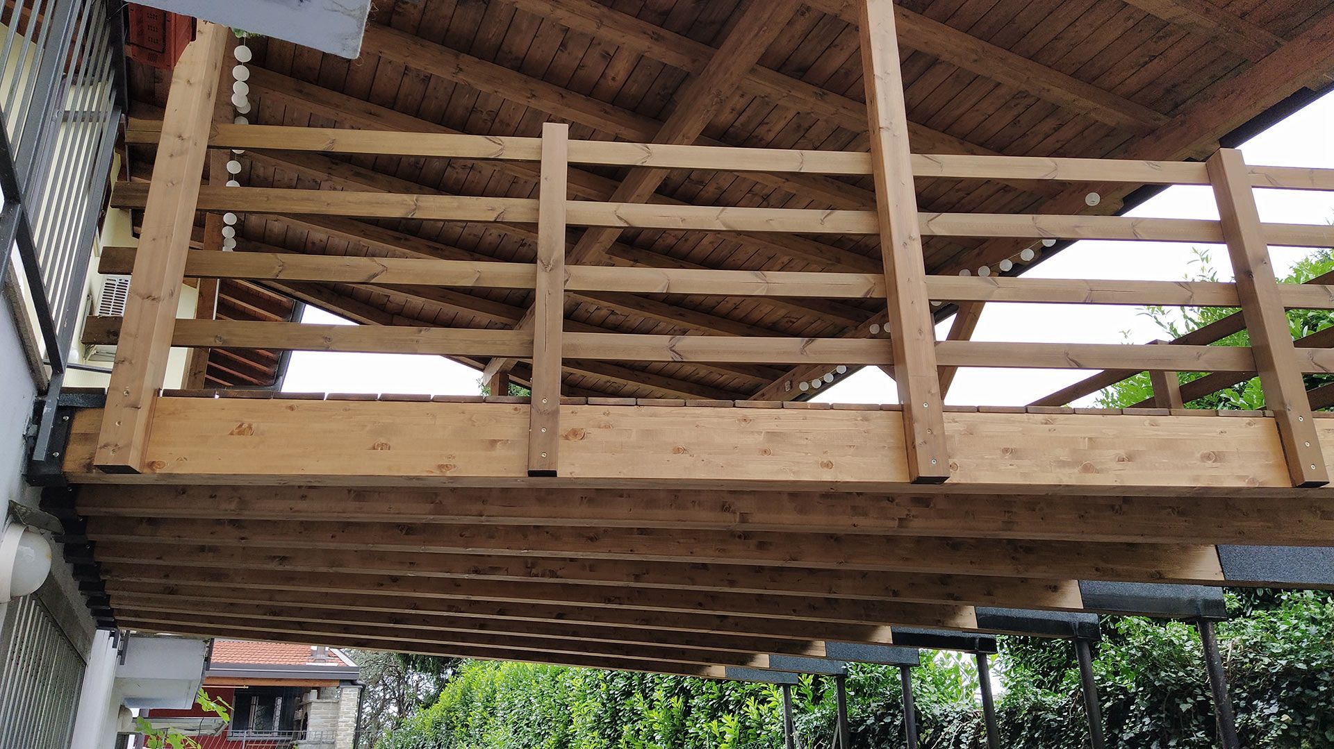 Soppalco in legno sotto un tetto di paglia, visto dal basso, con ringhiere e travi a vista.