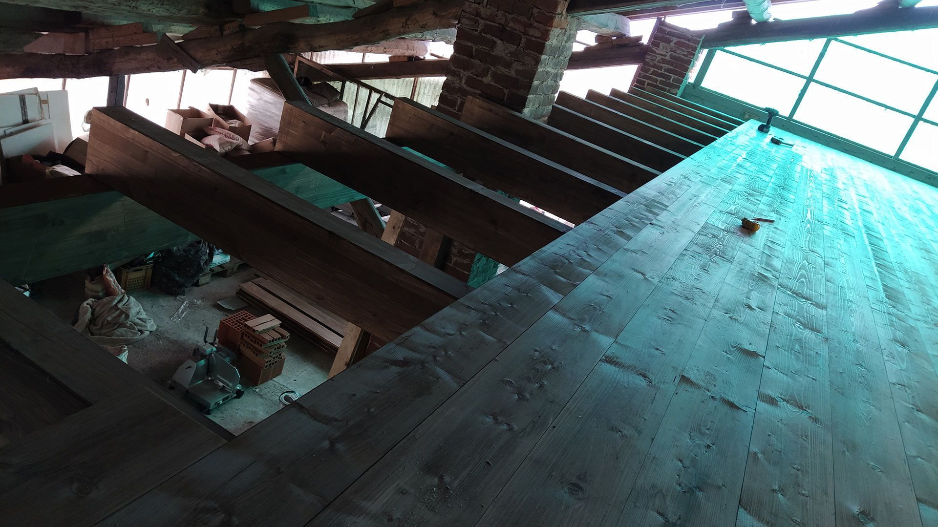 Vista inclinata di una scala di legno fatiscente con gradini rotti e detriti all'interno di un ambiente poco illuminato.