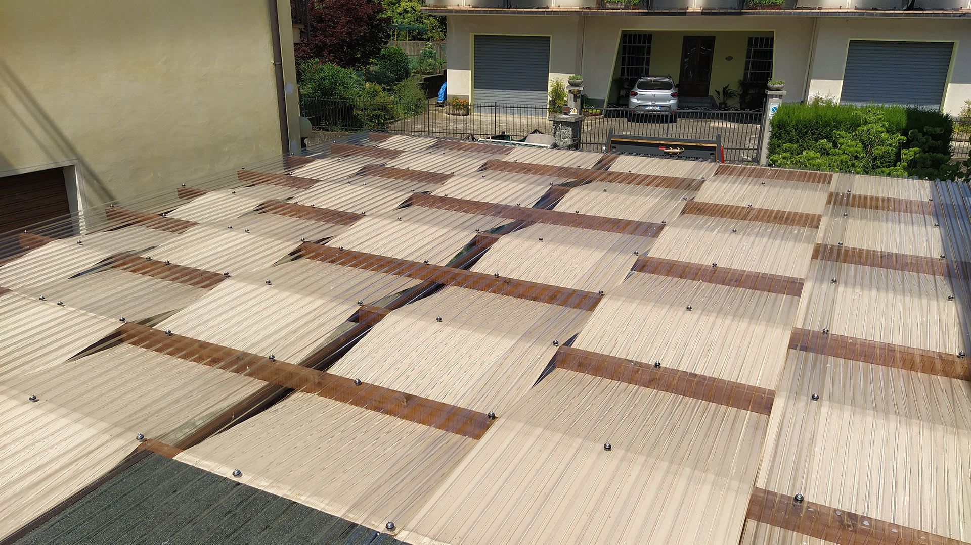 Patio esterno ricoperto da un patchwork di stuoie beige e marroni di fronte all'ingresso di un edificio.