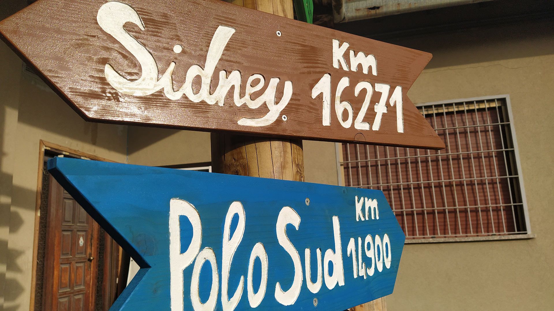 Cartelli di legno che indicano Sydney e Polo Sud, con le distanze in chilometri.