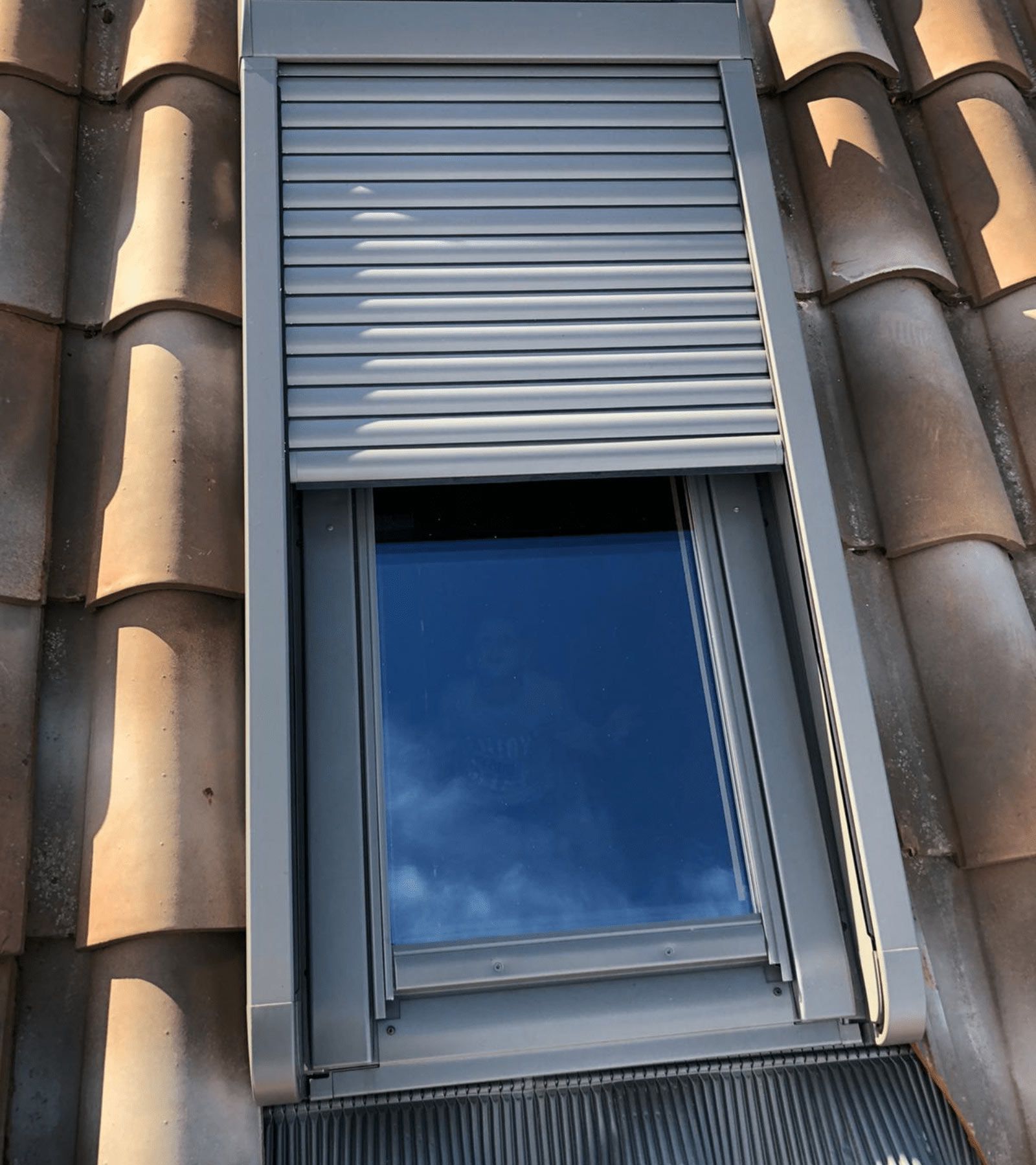 Persiana argentata chiusa sulla facciata di un edificio in pietra beige.