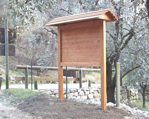 Cartello informativo in legno su pali in un parco alberato