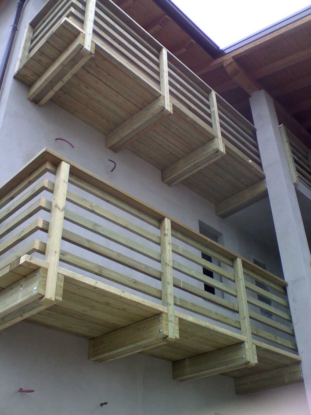 Balconi in legno con ringhiere di colore chiaro sulla facciata esterna di un edificio.