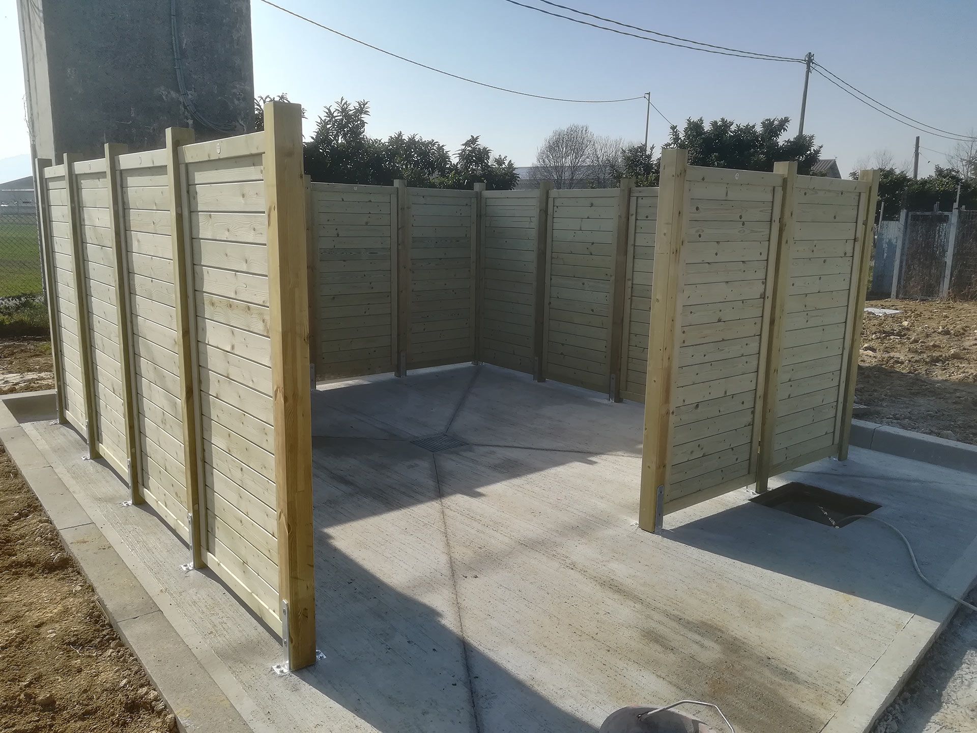 Pannelli di recinzione in legno per garantire la privacy intorno a un piccolo recinto in cemento all'aperto.