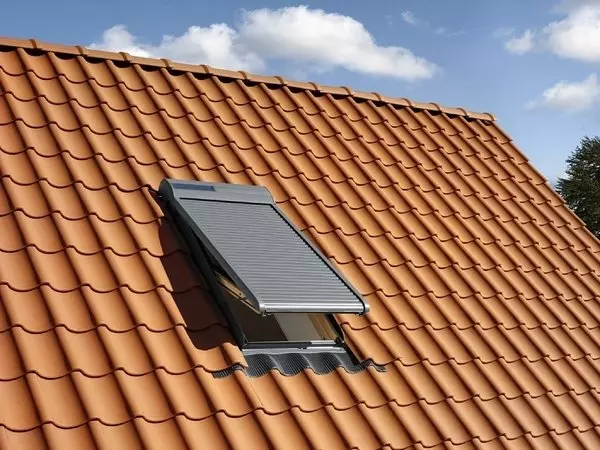 Lucernario sul tetto di una casa con le tegole in terracotta sotto un cielo azzurro