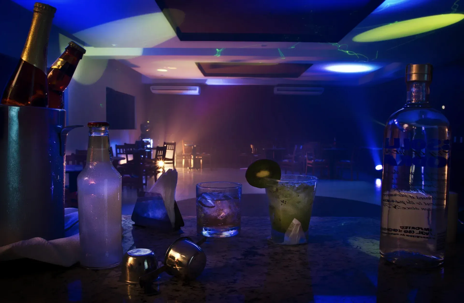Um bar com garrafas e copos de álcool.