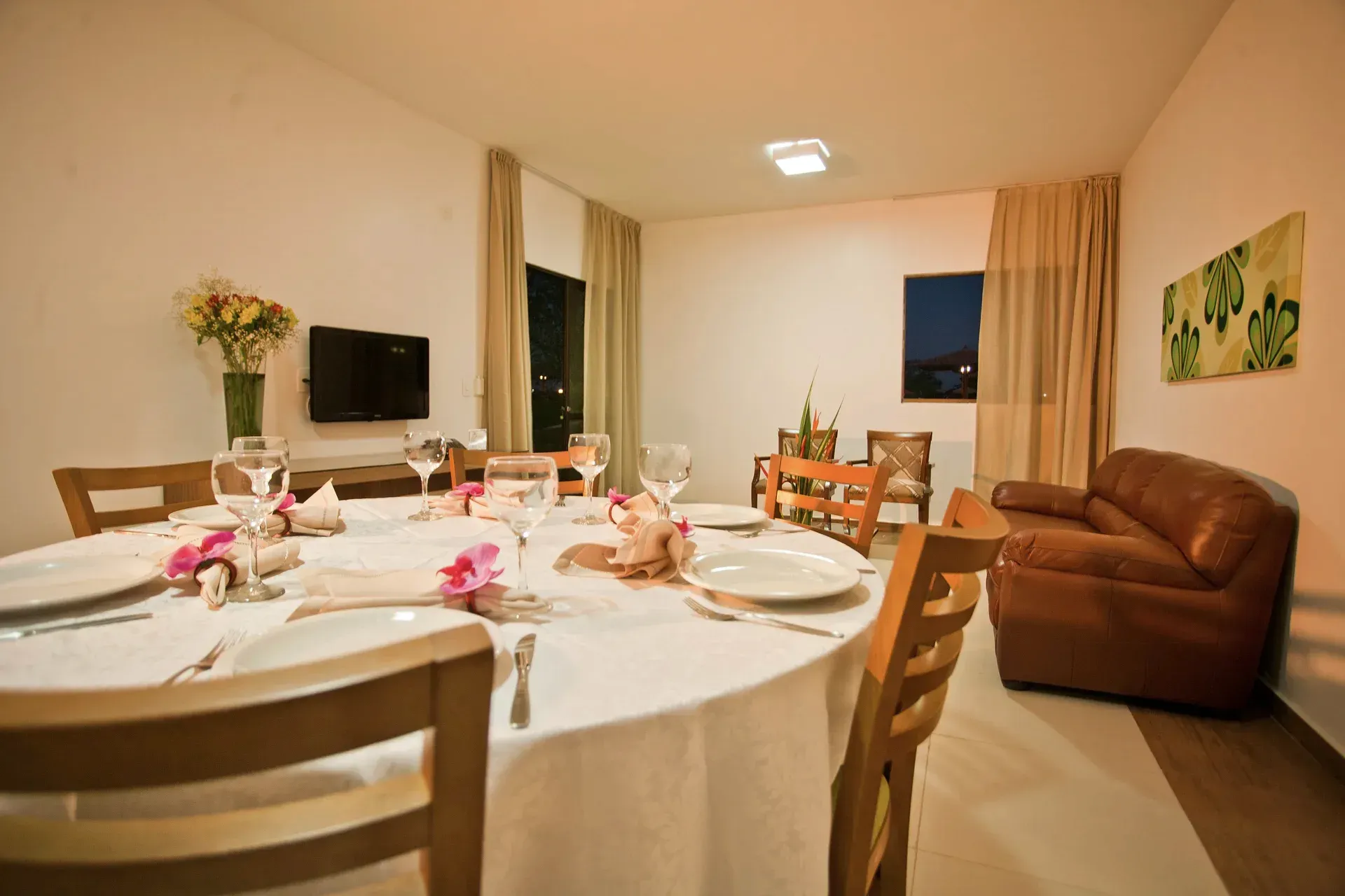 Uma sala de jantar com uma mesa redonda, cadeiras e um sofá.