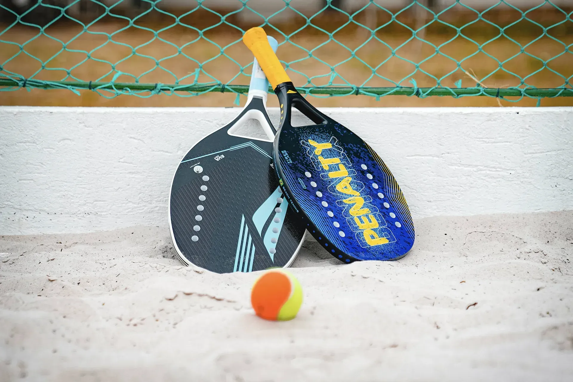 Duas raquetes de tênis de praia e uma bola na areia
