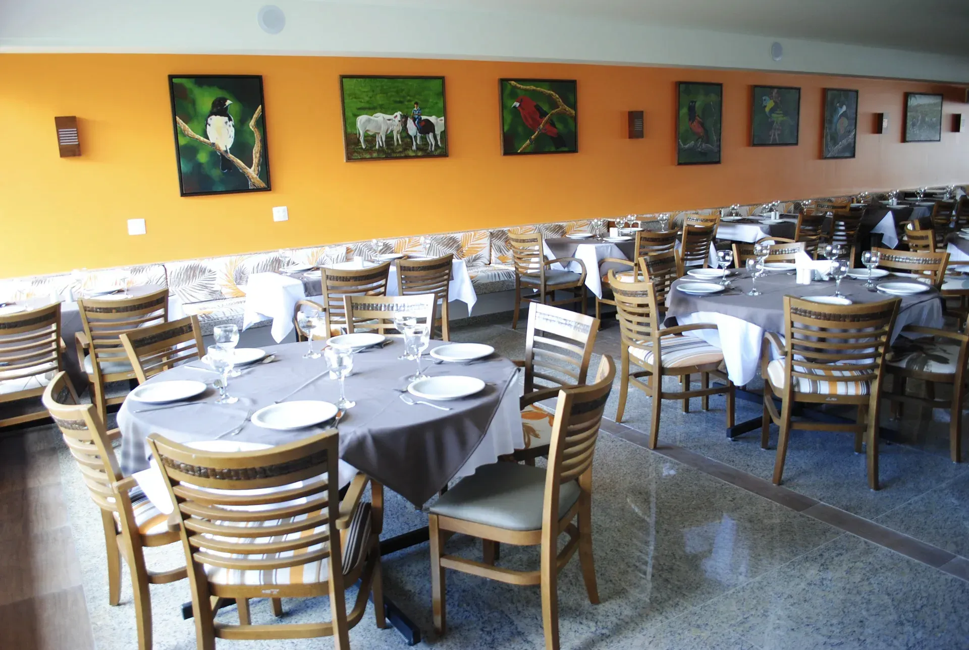 Uma sala de jantar com mesas, cadeiras e pinturas na parede