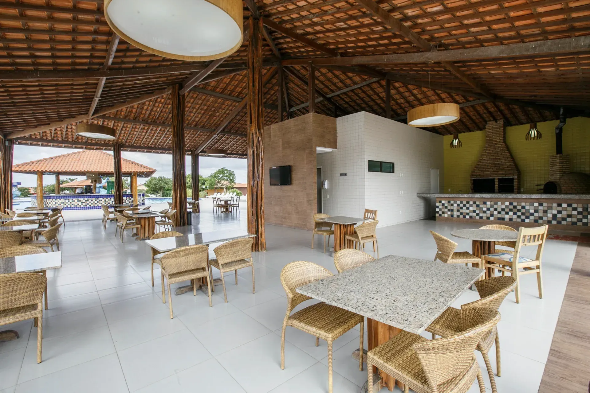 Uma sala grande com mesas e cadeiras sob um teto de madeira.