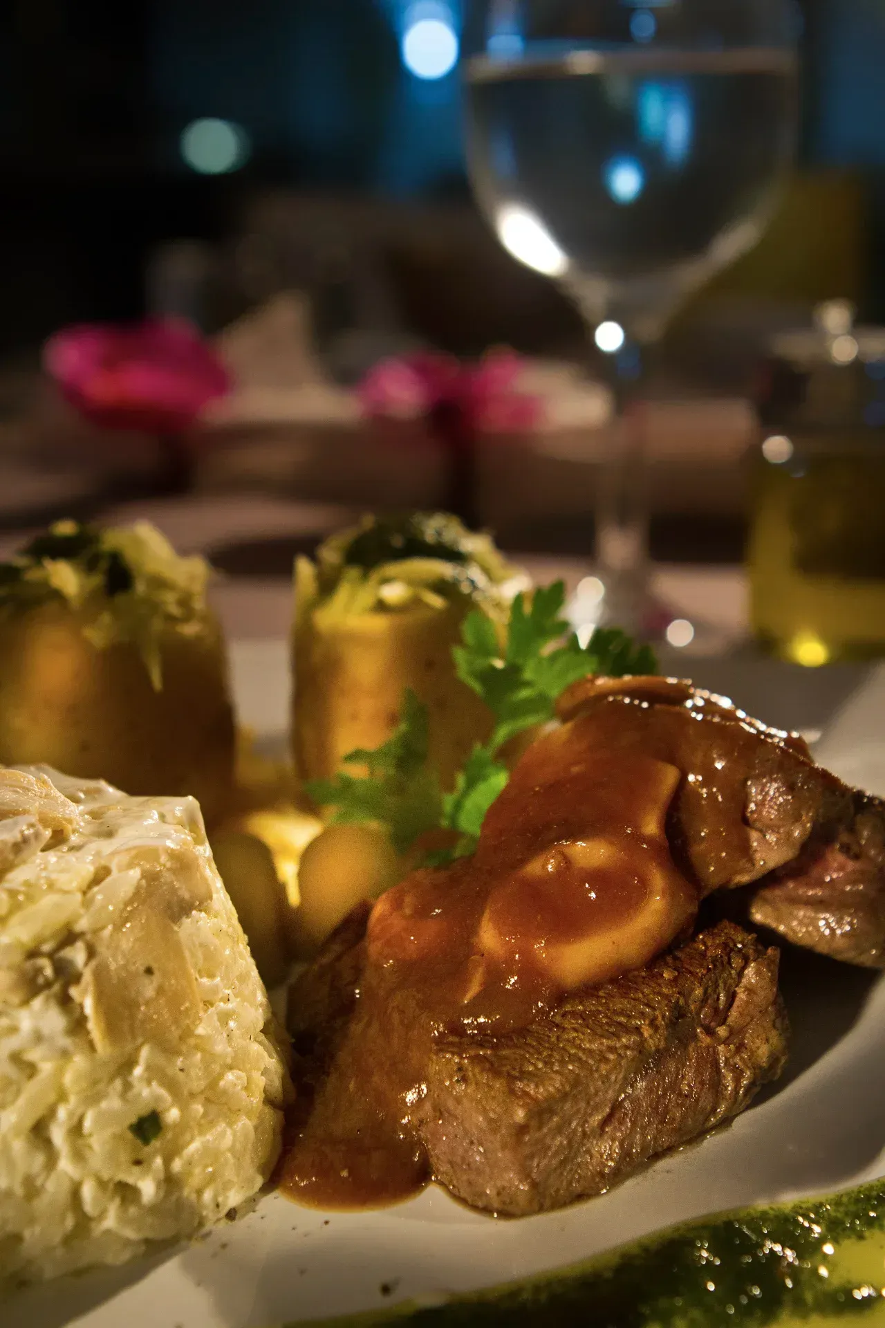 Um close de um prato de comida com uma taça de vinho ao fundo