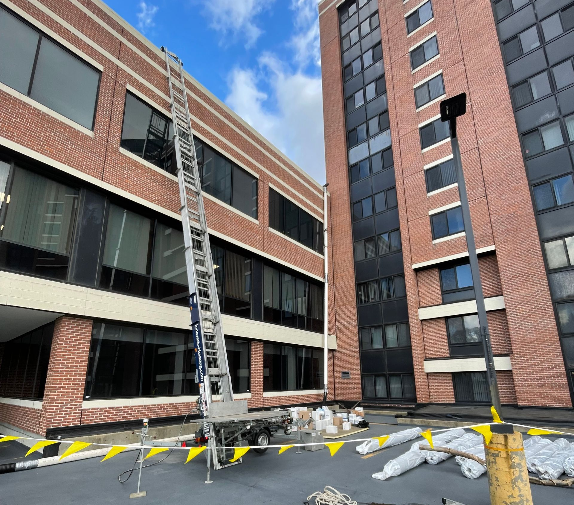 Roofing crew using an inclined material hoist to lift shingles onto a residential roof