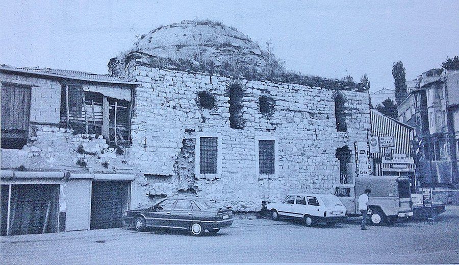 A black and white photo of a building with cars parked in front of it