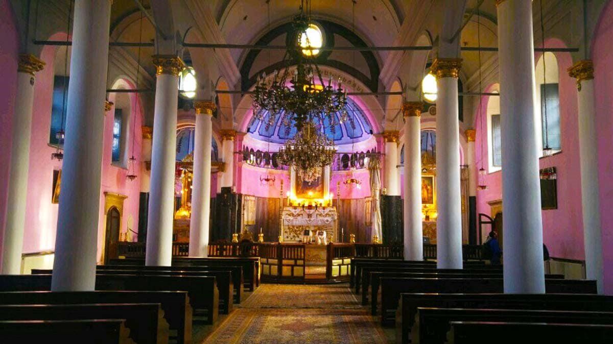 The inside of a church with rows of benches and columns.