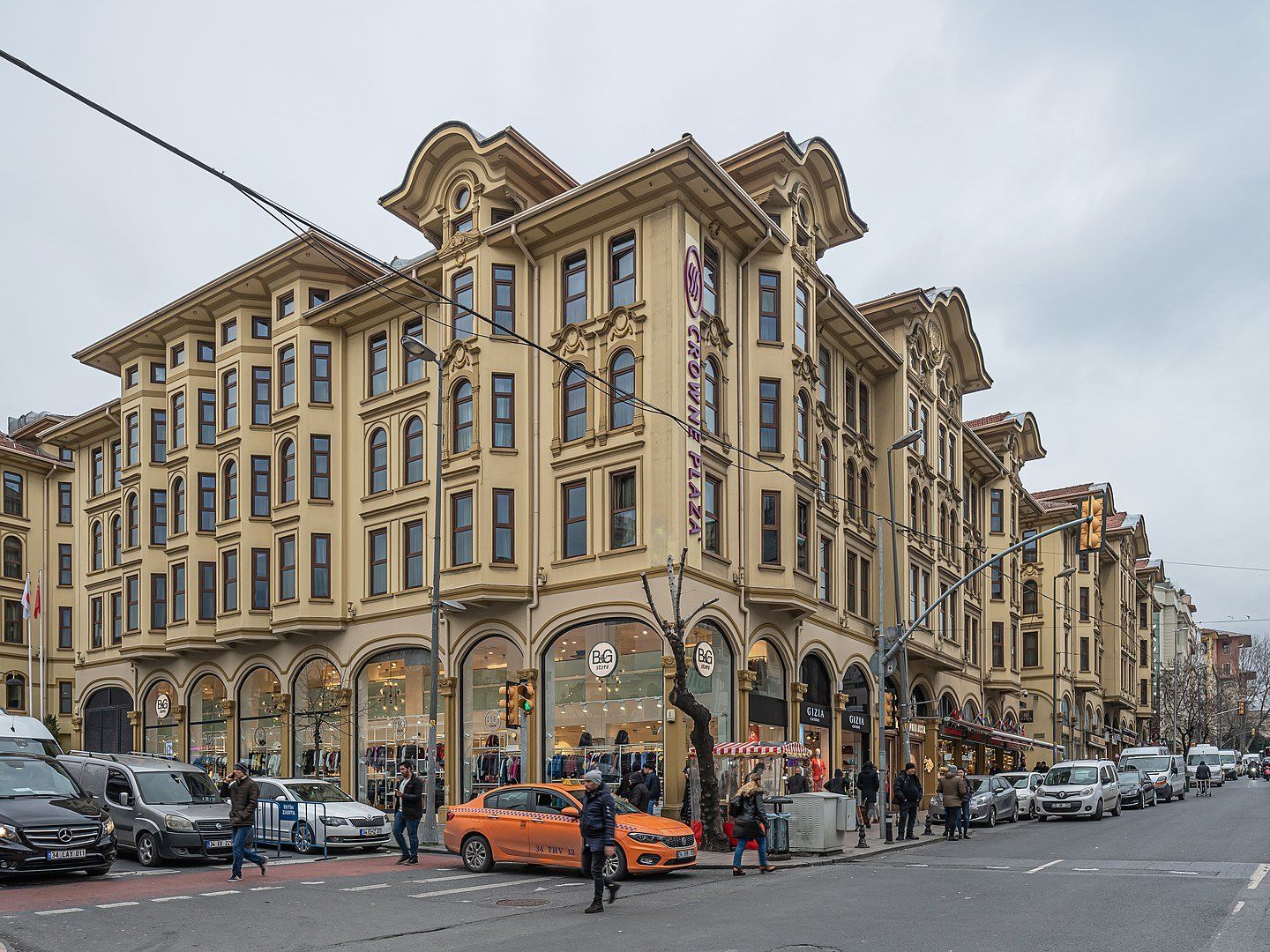 A large building with a lot of windows is on the corner of a street.