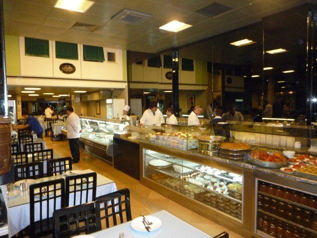 A restaurant with tables and chairs and a counter full of food