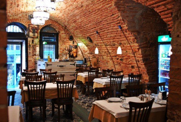 A restaurant with tables and chairs and a green fridge