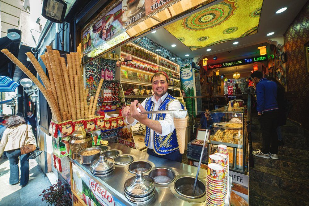 A man is standing behind a counter selling ice cream cones.
