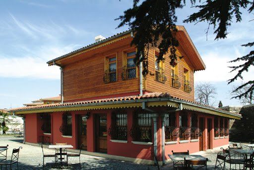 A red house with tables and chairs in front of it