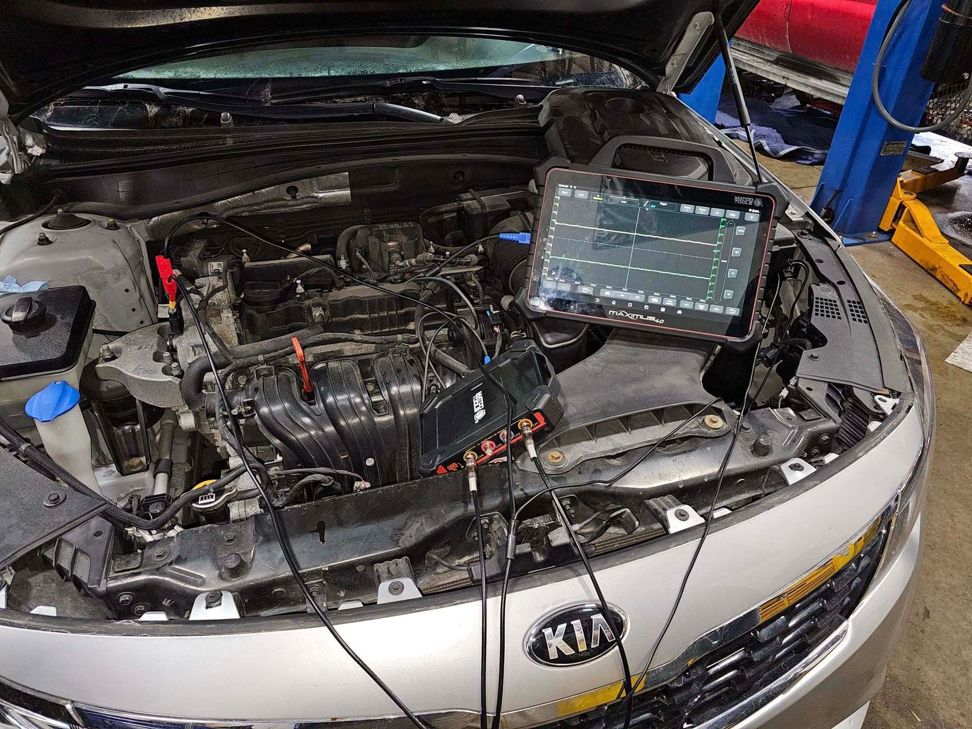 Kia sedan with hood open in a repair shop, engine exposed and diagnostic tablet mounted on the front | Best Choice Service