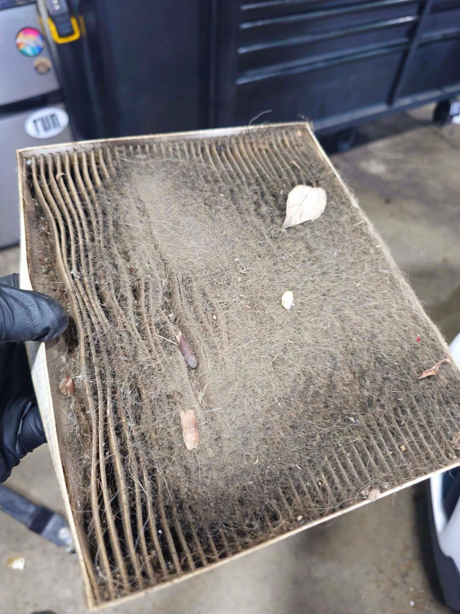 Dirty rectangular air filter held in a gloved hand, clogged with dust and debris | Best Choice Service