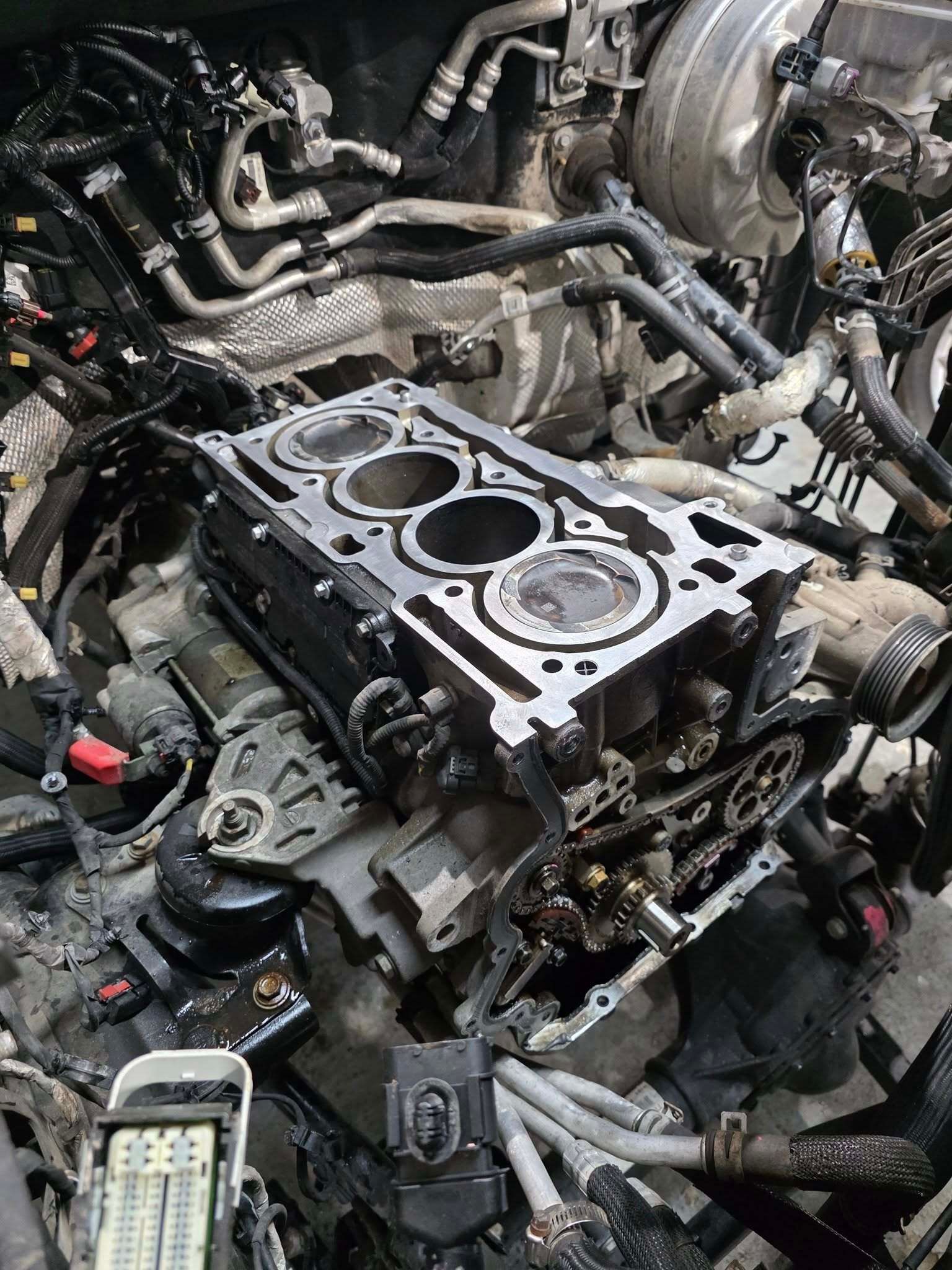 Car engine bay with exposed cylinder head and hoses during repair, tools scattered around | Best Choice Service