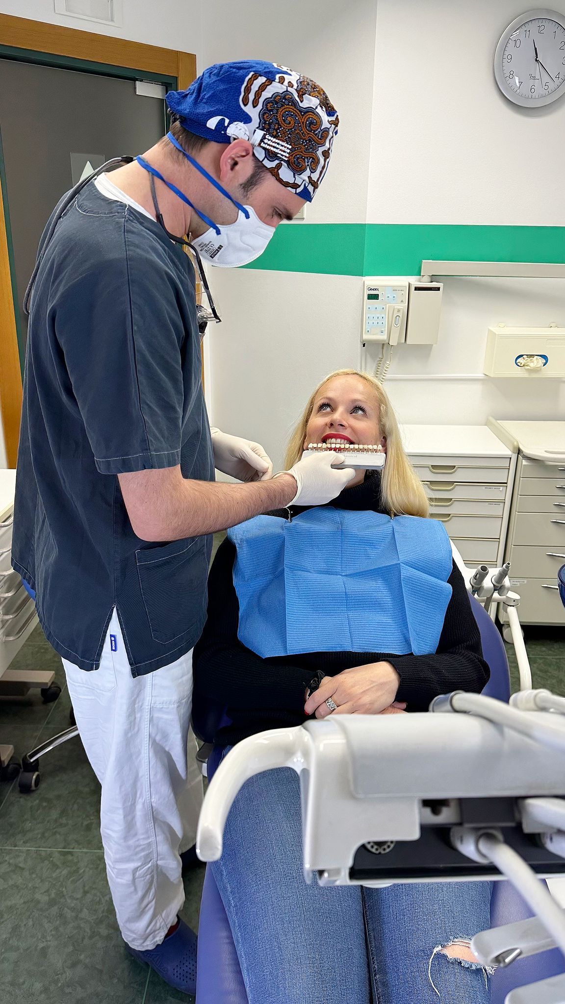 Un dentista visita un paziente sorridente in uno studio dentistico, indossando guanti e mascherina.