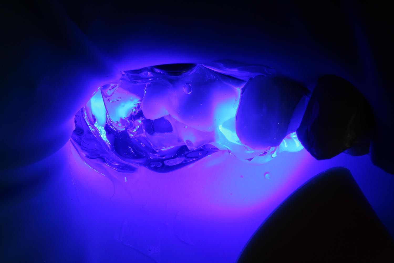 Cristallo blu-violaceo luminoso illuminato nell'oscurità