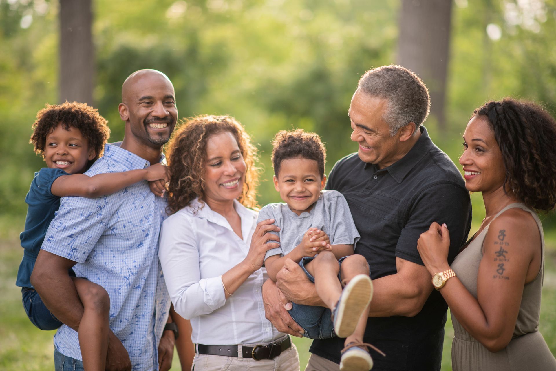 Family smiling, gathered in a circle, looking down at the camera outdoors.
