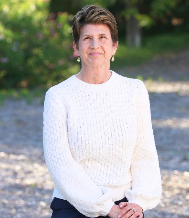 A woman in a white sweater smiles for the camera