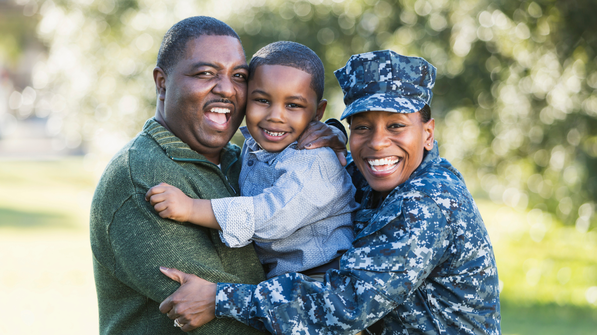 A man and woman in military uniforms are holding a little boy in their arms.