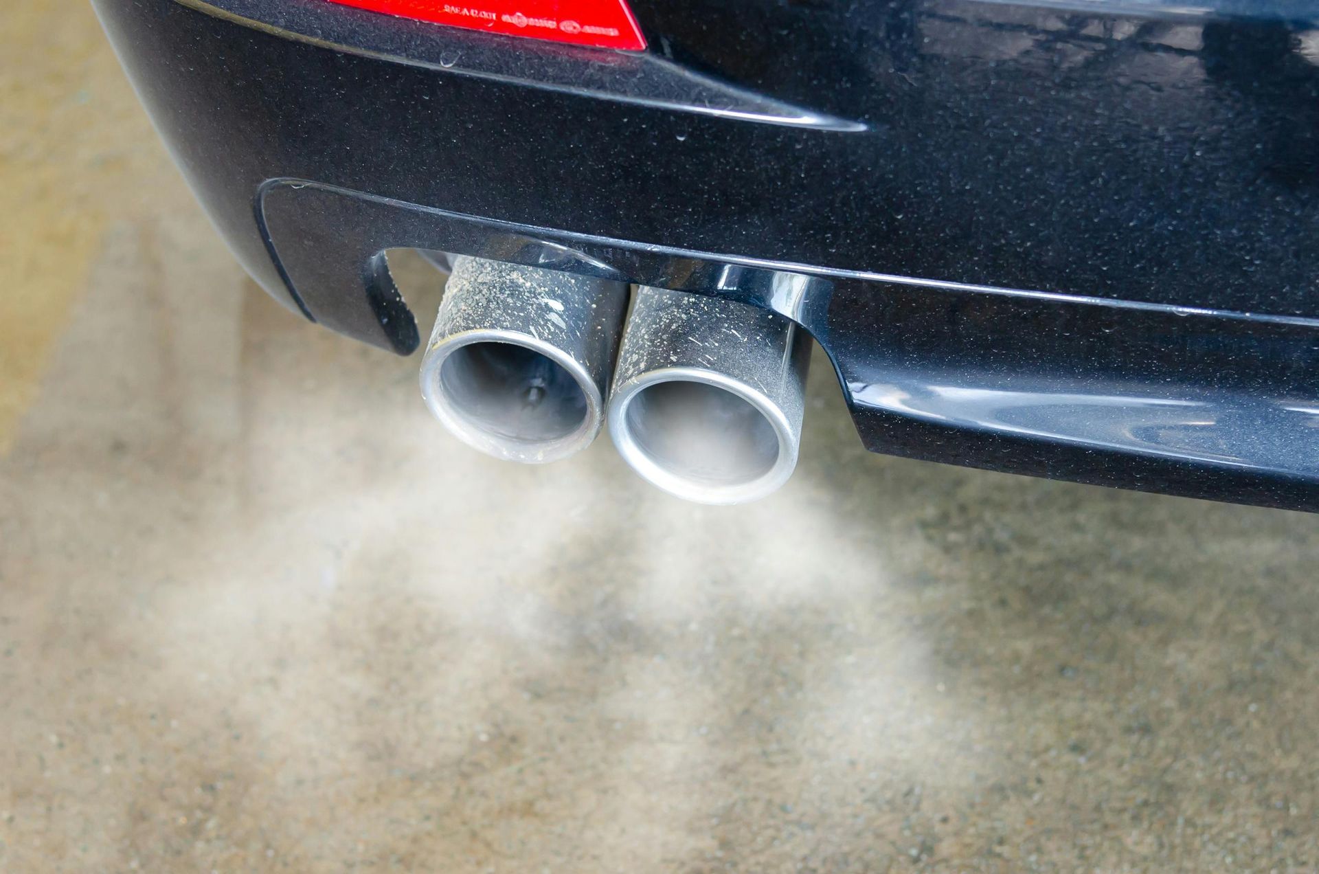 Smoke is coming out of the exhaust pipes of a car.