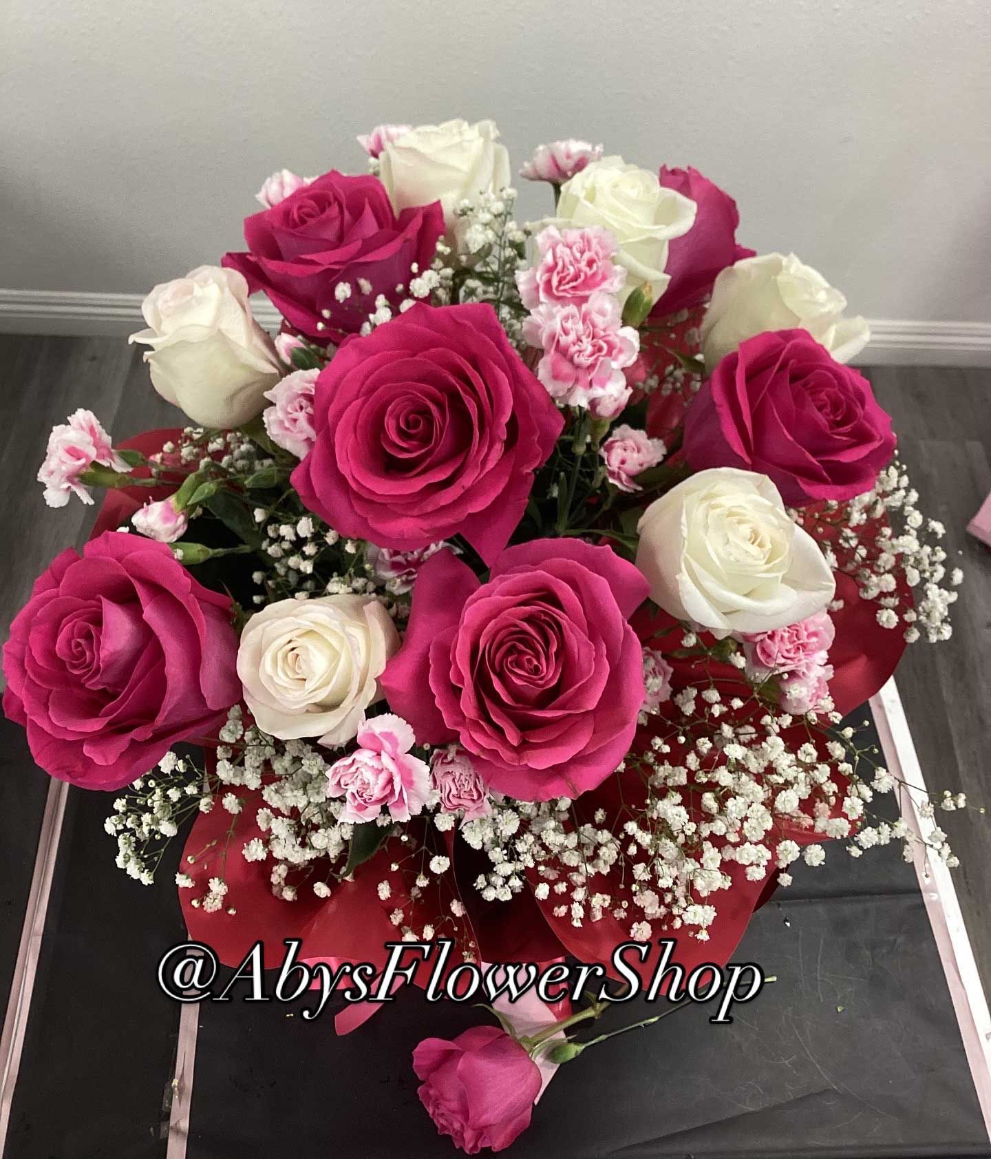 A floral arrangement of deep pink and white roses, accented with small pink carnations and baby's breath.