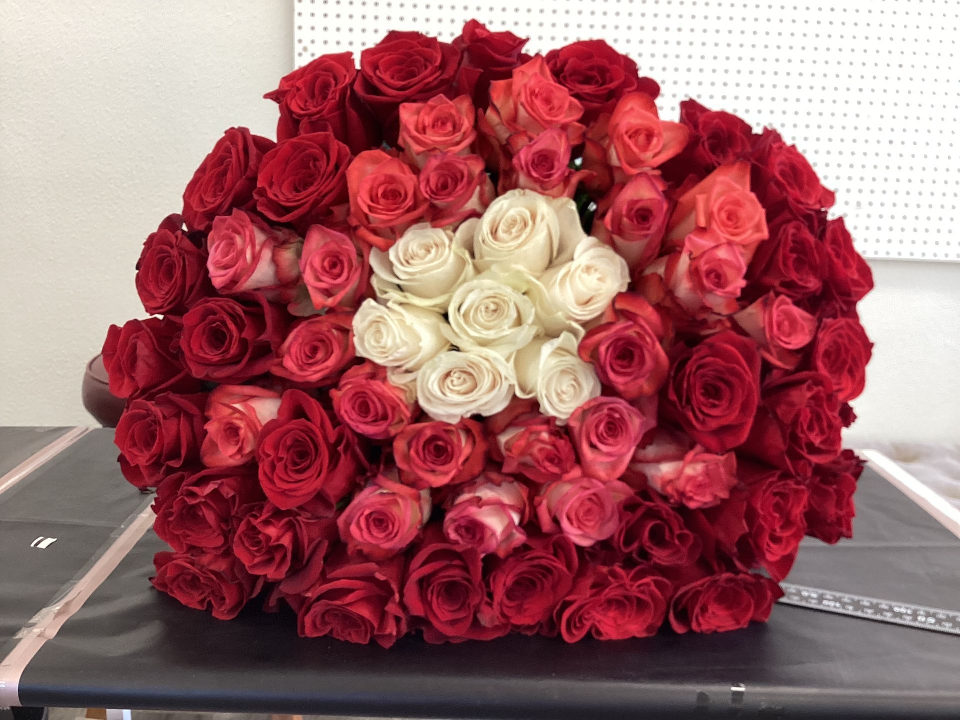 A dense, circular bouquet of deep red roses featuring a cluster of white roses at its center.