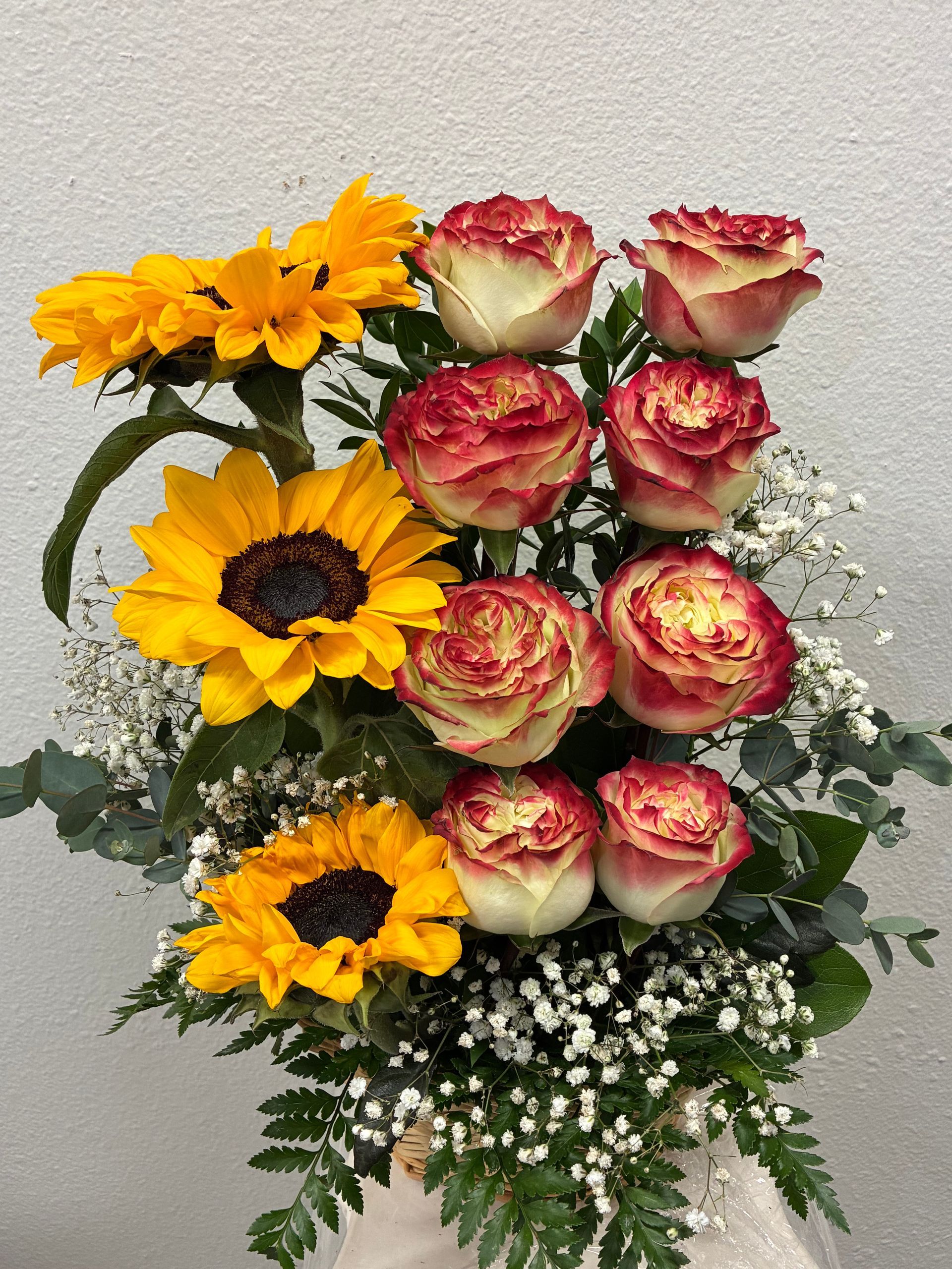 A bouquet of yellow sunflowers and white-and-red bi-color roses, accented with baby's breath and greenery.