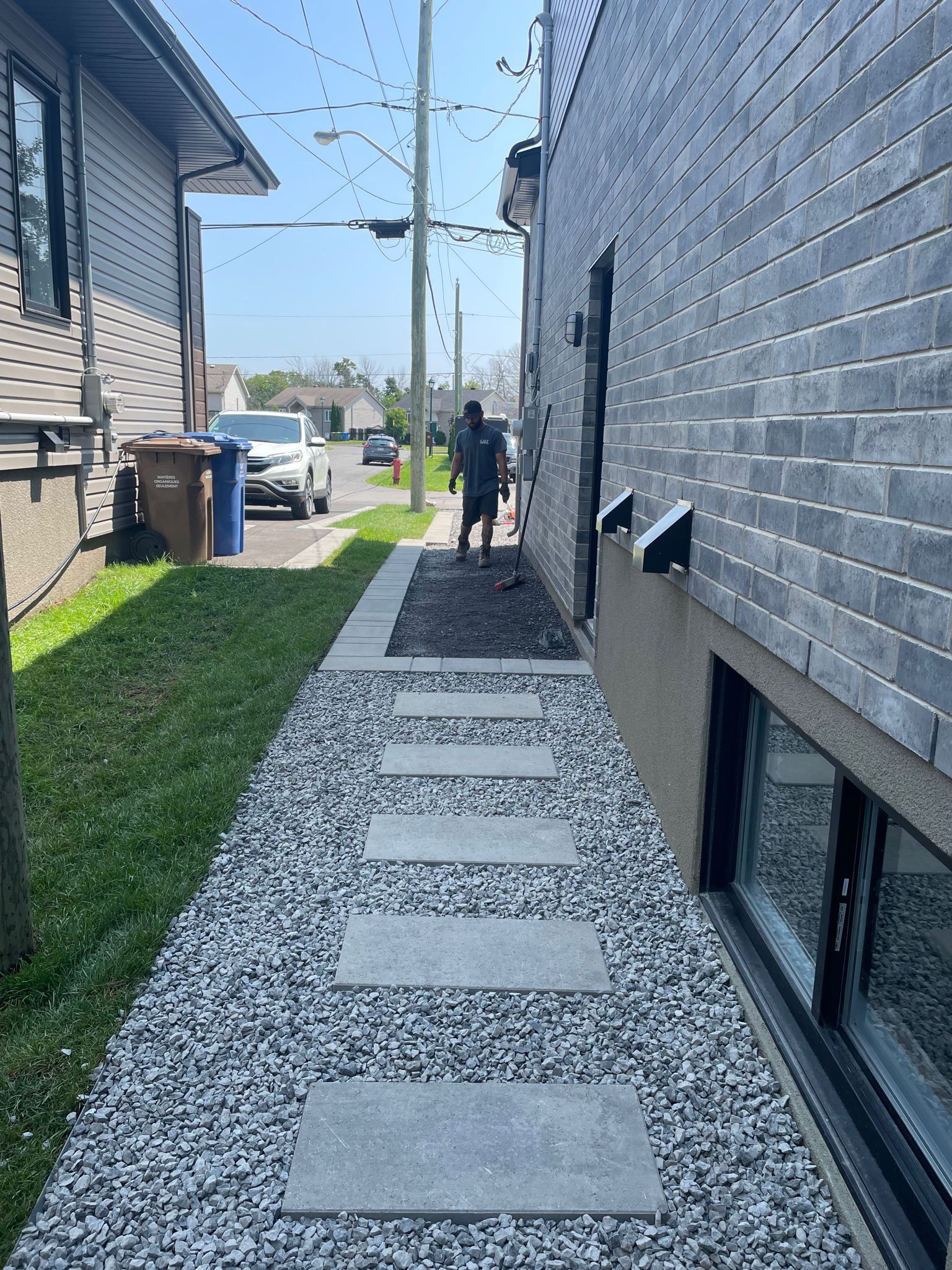 Un homme marche sur un trottoir à côté d'un bâtiment en briques.