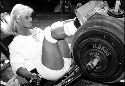 A woman is using a leg press machine with a weight of 11.2 kgs