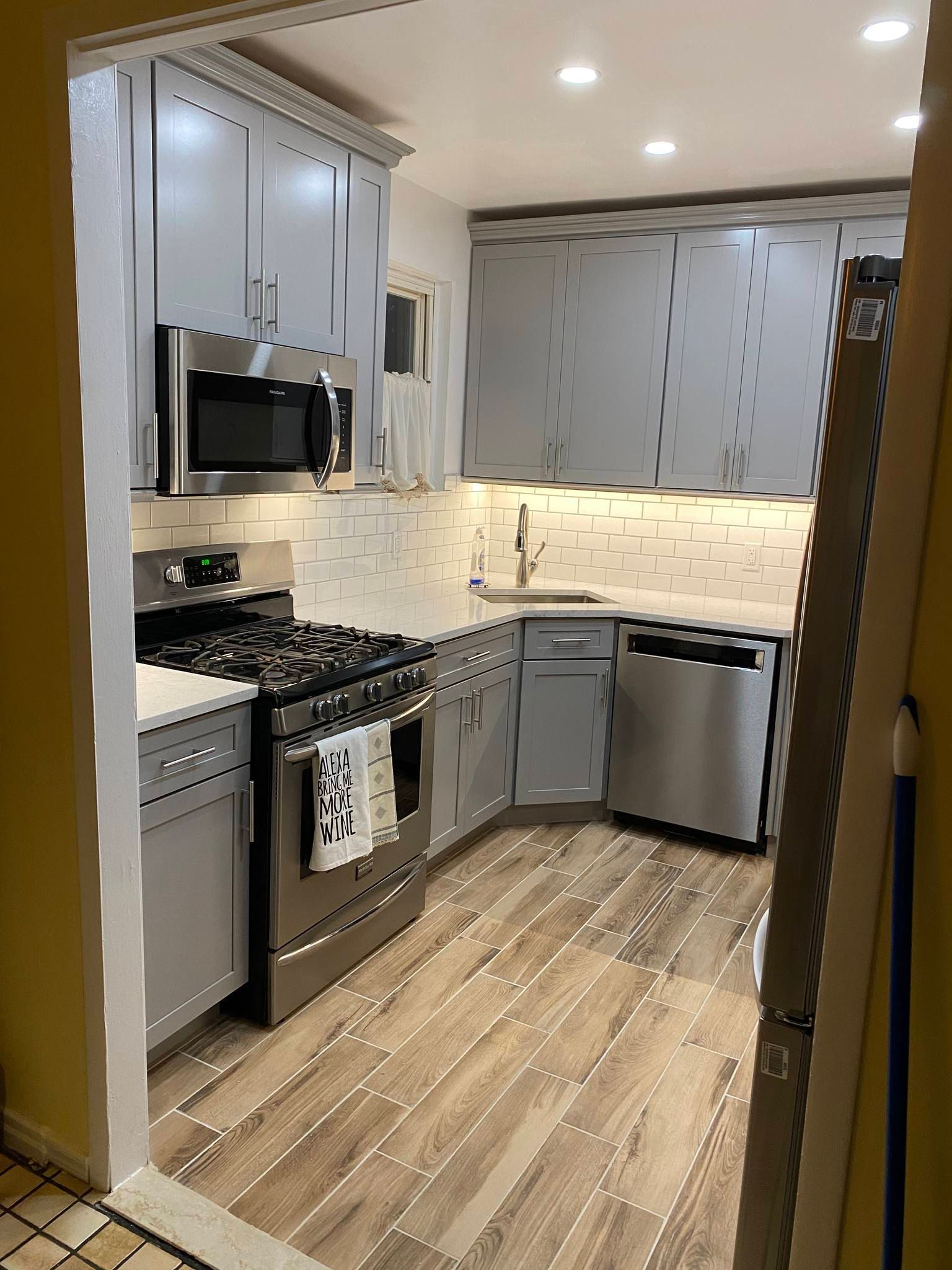 Open-concept kitchen with dark cabinets, an island, and hardwood floors; connected to a hallway.