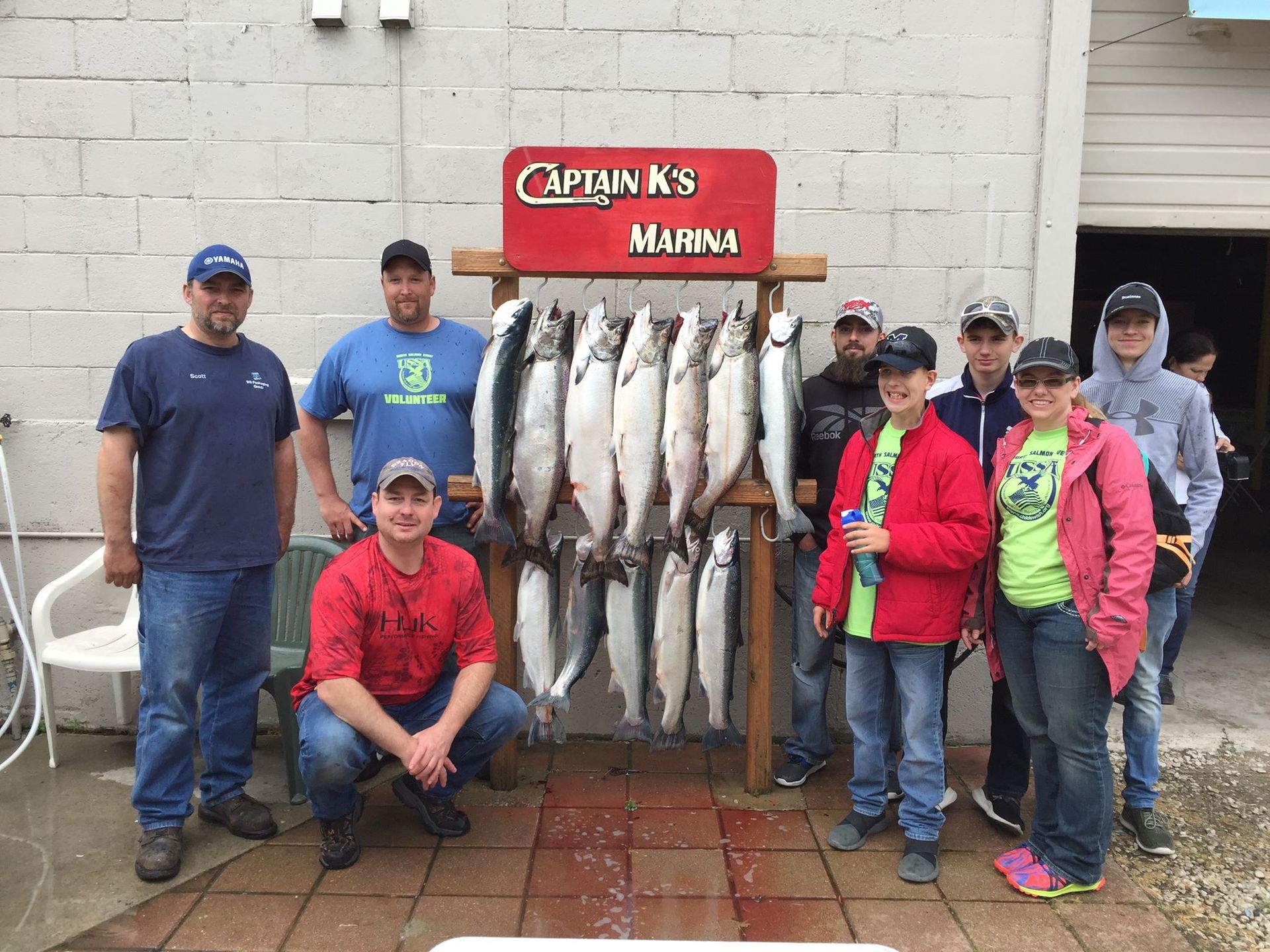 A group of people are posing for a picture in front of a display of fish at Captains Marina