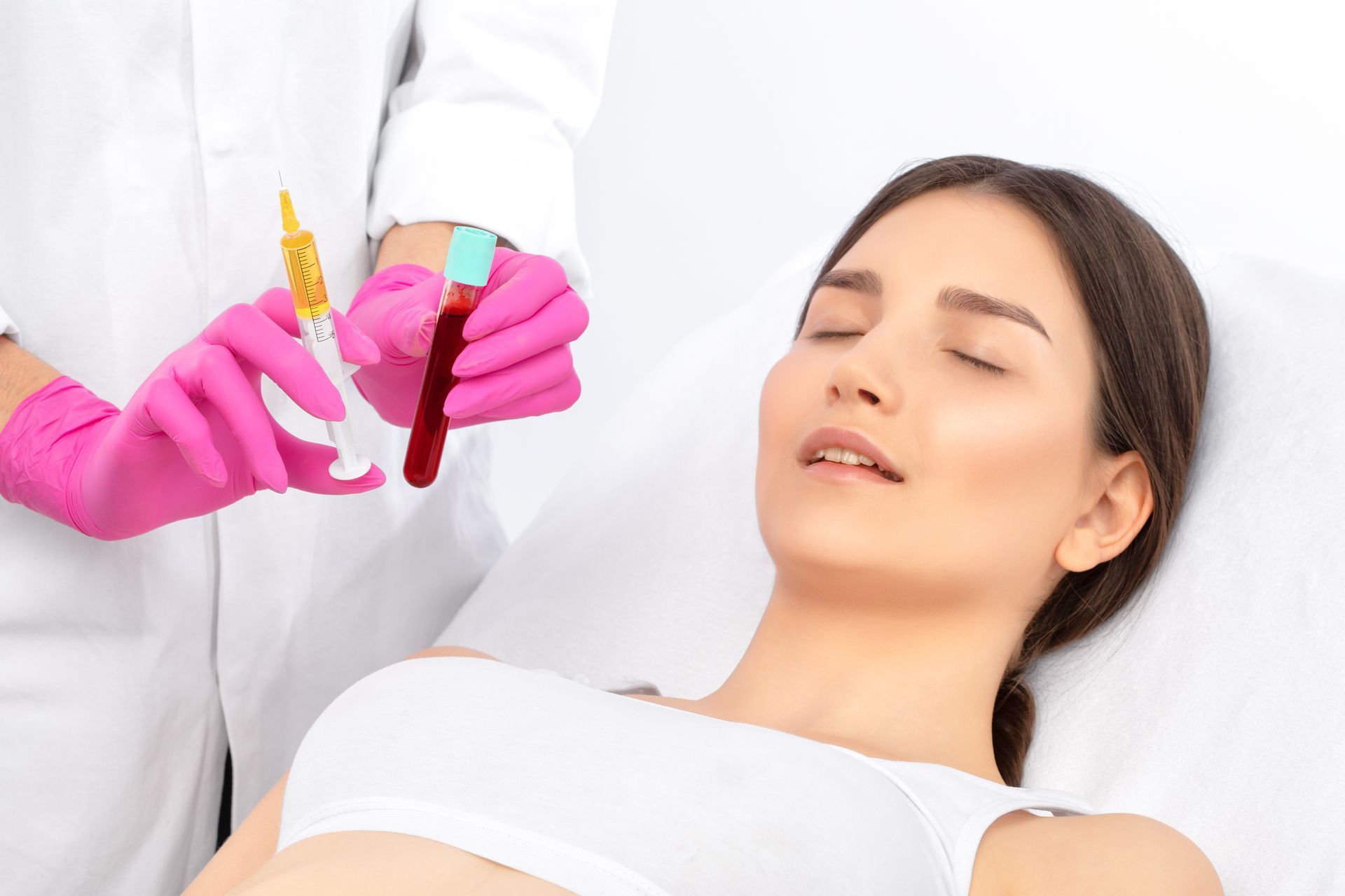 Gloved clinician prepares syringe near a relaxed patient lying on a treatment bed