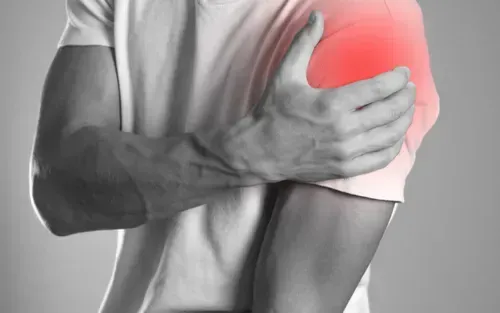 Person clutching a red-highlighted shoulder, indicating shoulder pain or injury
