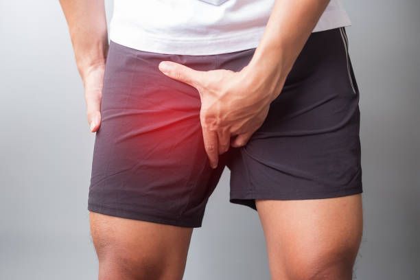 Person holding groin with red pain highlight on inner thigh