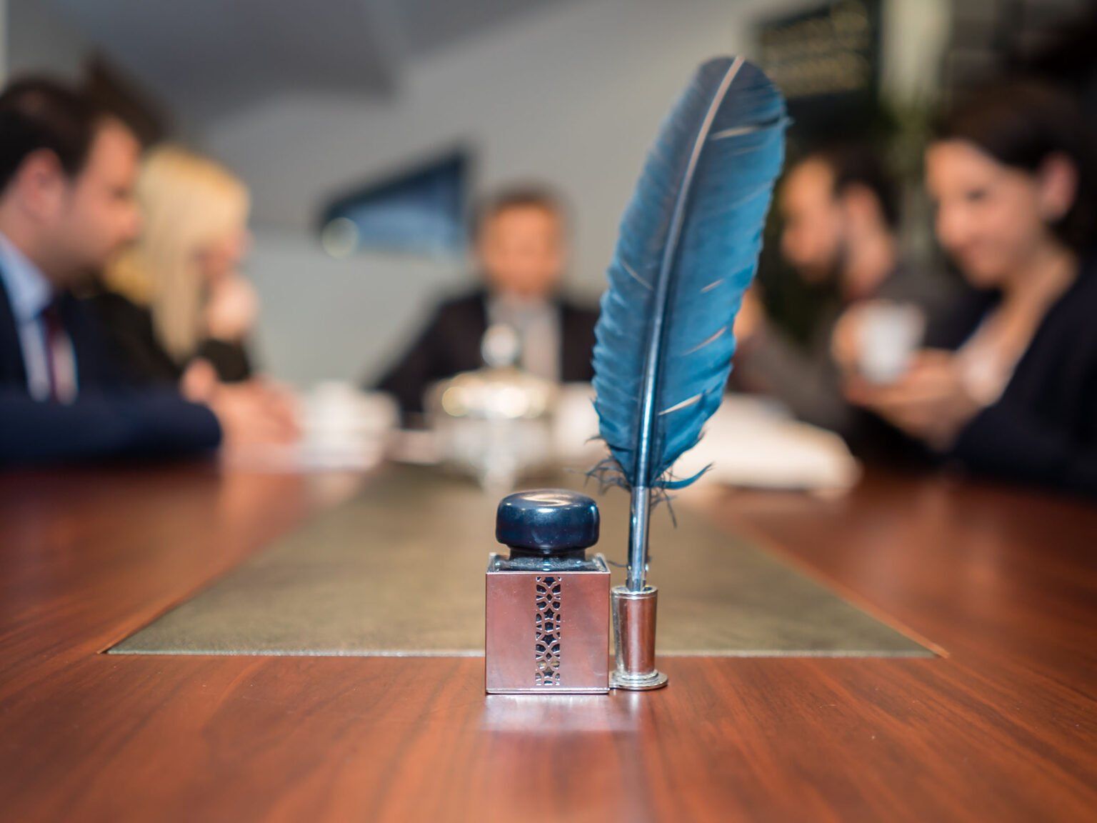 A feather pen is sitting on a table in front of a group of people