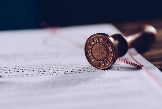 Notarized document with apostille certificate, notary stamp, passport, and legal paperwork on a desk