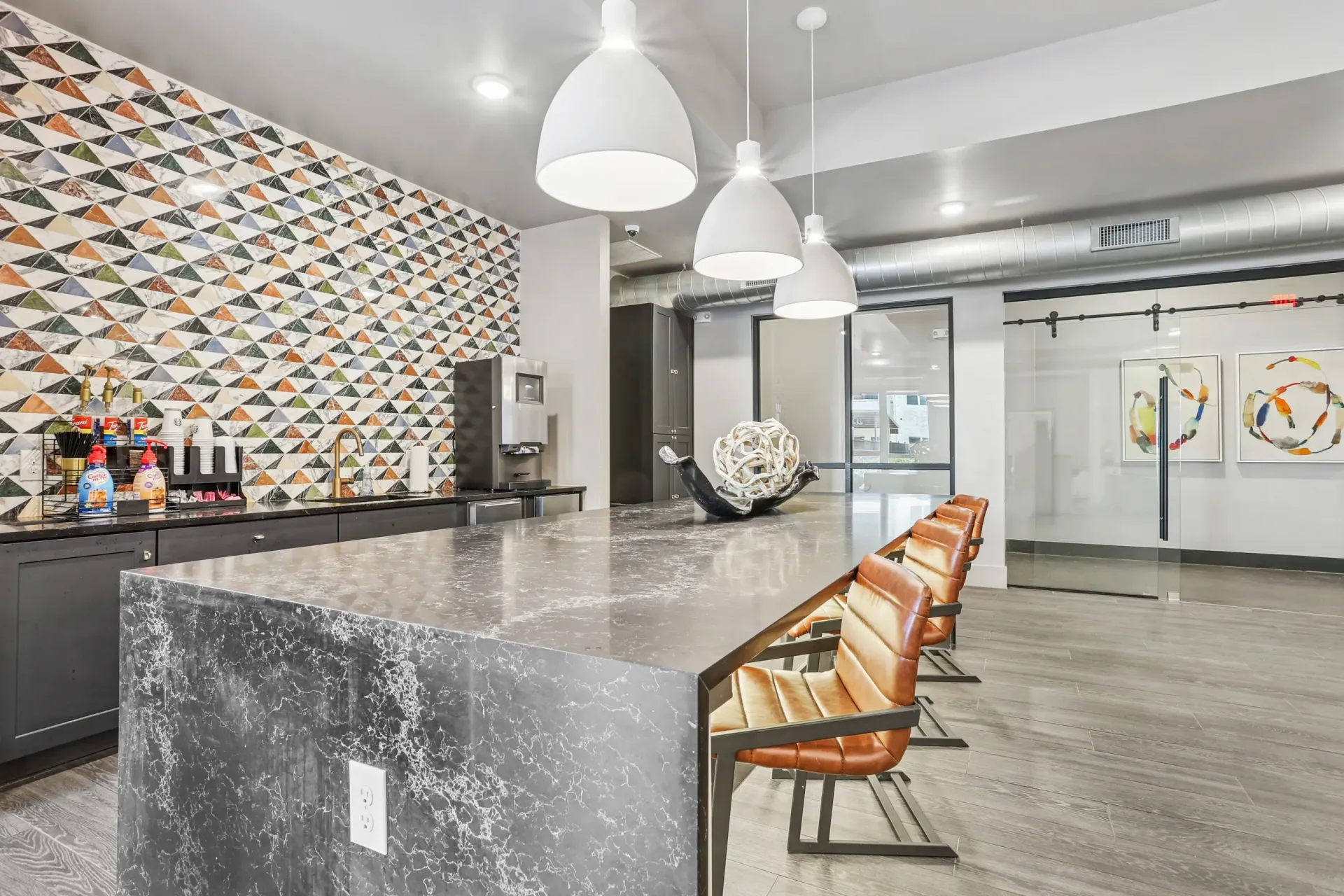Community lounge with marble bar island, pendant lights, and a coffee station.