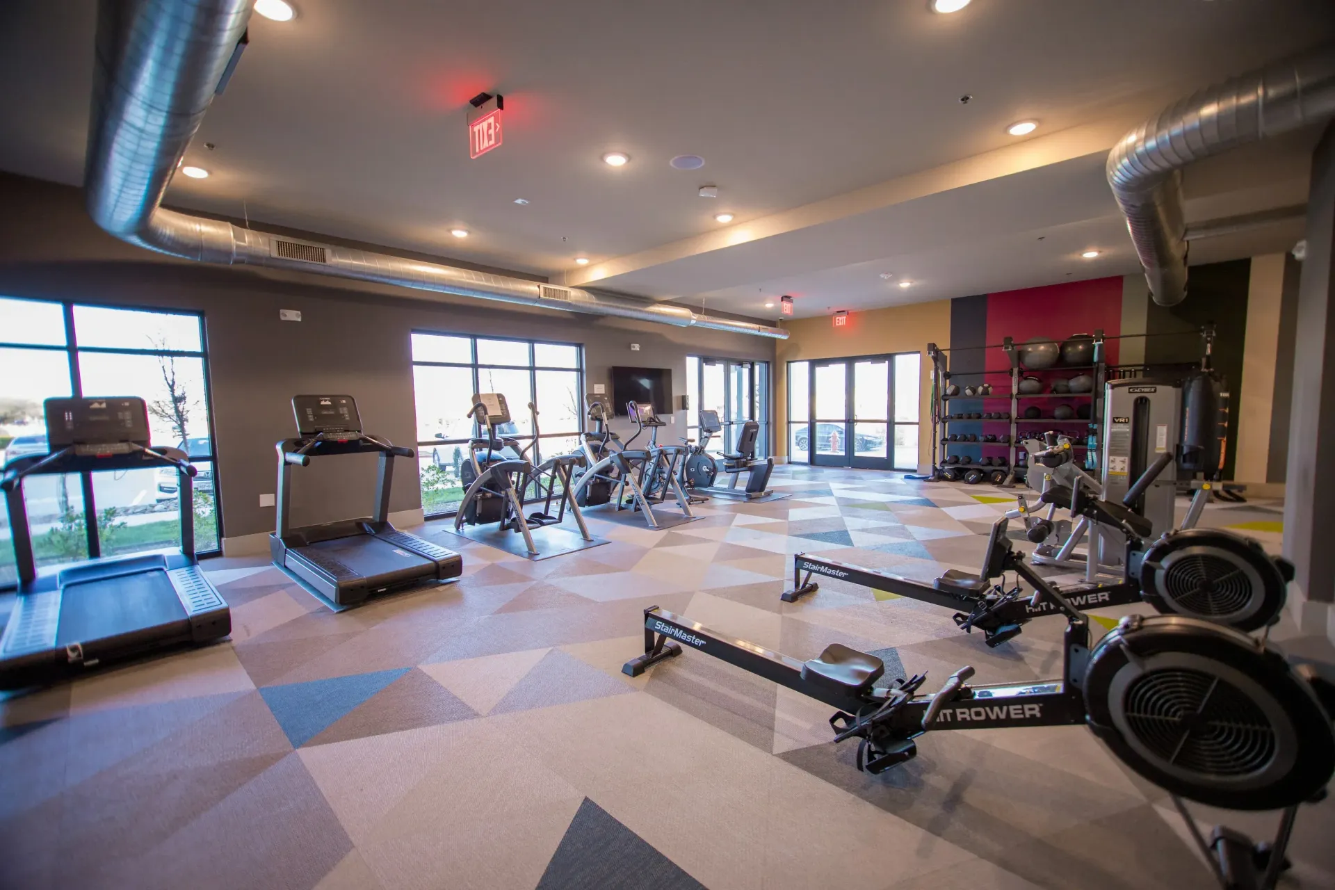 Indoor gym within the multifamily community featuring cardio machines and weights.
