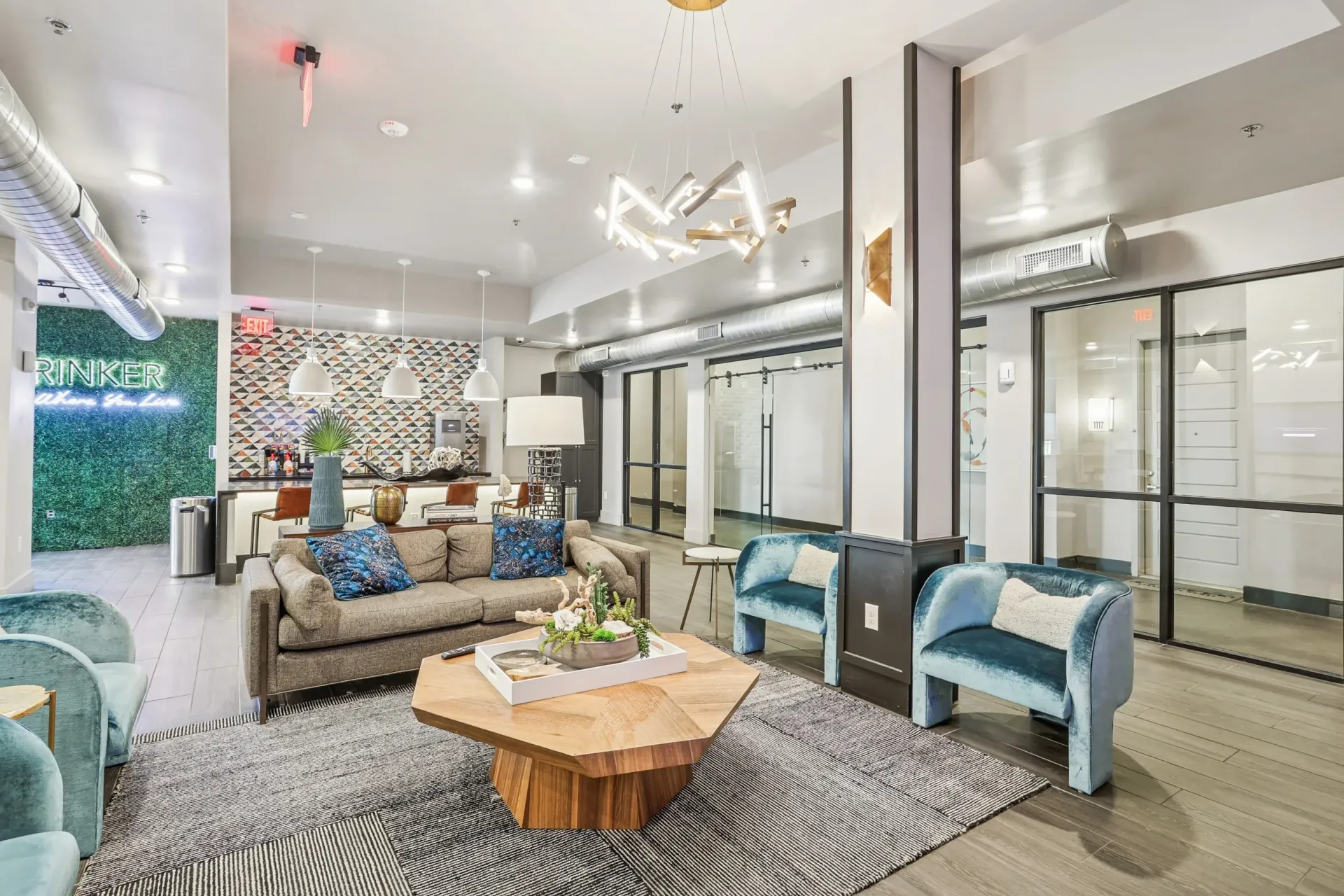 Contemporary community lounge with sofa seating, blue accent chairs, and a bar area.